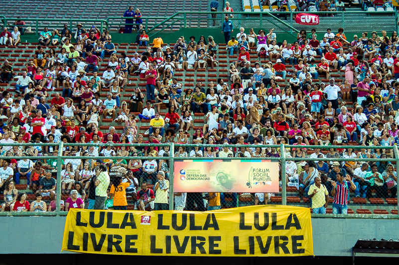 A Assembleia das Democracias, sediada ontem (15) no estádio do Pituaçu, zona norte de Salvador, parte da programação do Fórum Social Mundial, começou de verdade quanto, aos gritos de “olê olê olê olá, Lula, Lula”, o furioso público irrompeu através das cercas de metal que os distanciavam do palco, invadindo a área vip onde a grande maiorias das cadeiras de plástico, cuidadosamente dispostas em fila, quedavam quase que completamente desocupadas.