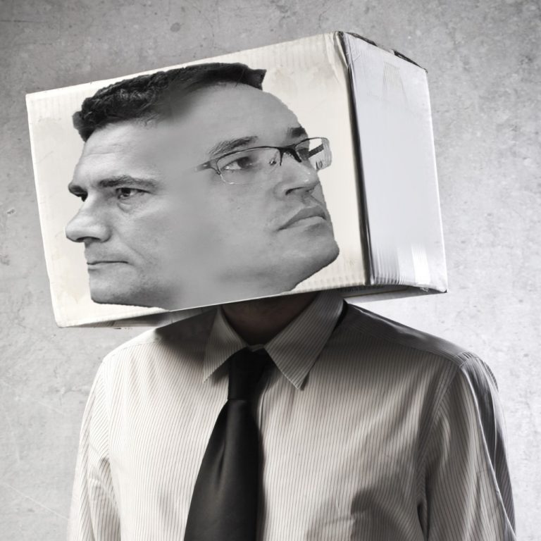 Imagem de torso com cabeça de caixa. Na caixa, aparecem os rostos de Deltan e Moro.