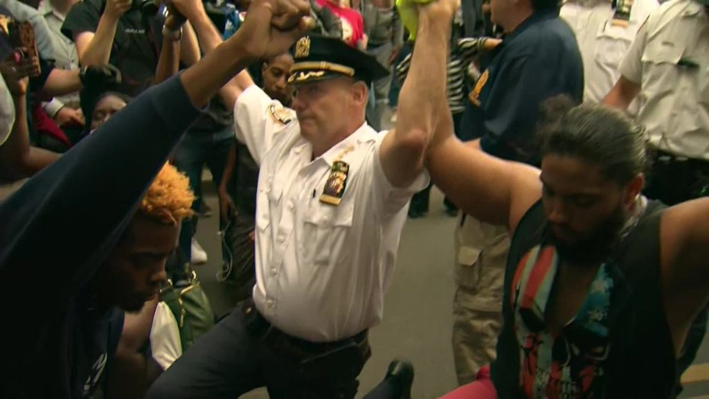 Crise permanente, revolta latente e conflagração iminente Oficial da polícia de Nova York abraçou e se ajoelhou com manifestantes em protesto contra o assassinato de George Floyd